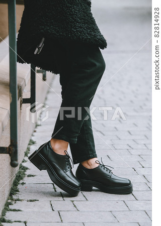 Close-up photo of young woman in black fur coat, jeanse and shoes at city street 82814928