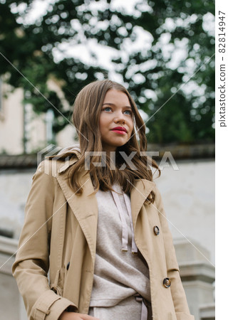 Portrait of fashionable women in beige sports suit and trench coat posing on the street Portrait of fashionable women in beige sports suit and trench coat posing on the street 82814947