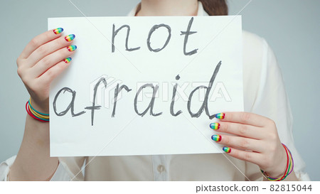 Photo of girl with rainbow nails holding poster 82815044