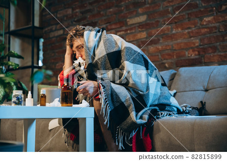 Cropped portrait of young sick boy having cold and flu, allergy. Running nose, sneezing. Home isolation Cropped portrait of young sick boy having cold and flu, allergy. Running nose, sneezing. Home isolation 82815899