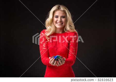Young beautiful emotional woman with chips in hands on a black background in the studio. Poker 82816623
