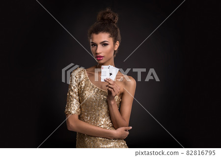 Woman winning - Young woman in a classy gold dress holding two aces, a poker of aces card combination. Woman winning - Young woman in a classy gold dress holding two aces, a poker of aces card combination. 82816795