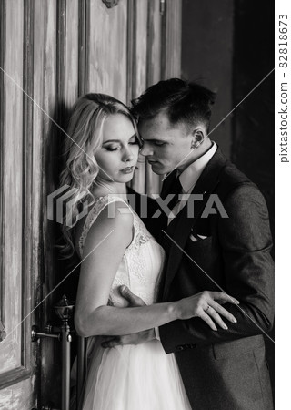 Cute wedding couple in the interior of a classic studio decorated. They kiss and hug each other. 82818673
