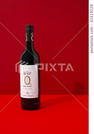 KYIV, UKRAINE - SEPTEMBER 22, 2021. Bottle of alcohol free Peter Mertes Just 0 wine on red background KYIV, UKRAINE - SEPTEMBER 22, 2021. Bottle of alcohol free Peter Mertes Just 0 wine on red background 82819229