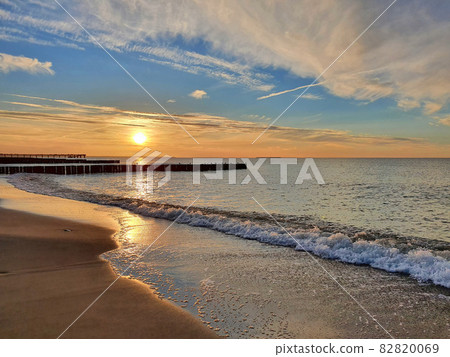 Beach on calm Baltic Sea under scenic sunset sky Beach on calm Baltic Sea under scenic sunset sky 82820069