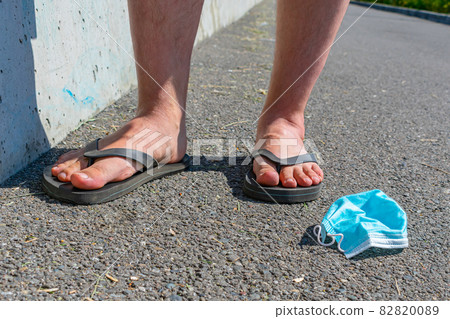 A medical mask is lying on the road under the feet of people A medical mask is lying on the road under the feet of people 82820089