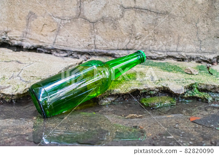 A bottle of expired beer thrown into a puddle 82820090