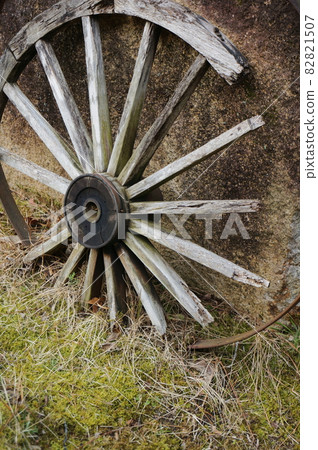 Large decayed and abandoned wooden wheels leaning against a sooted wall, maybe the wheels of an old cart, look nostalgic 82821507