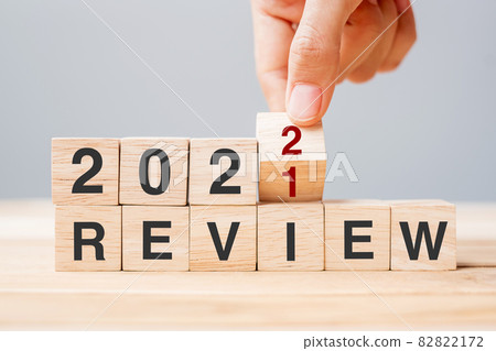 Businessman hand holding wooden cube and flip over block 2021 to 2022 REVIEW on table background. Resolution, goal, change, start and New Year holiday concepts Businessman hand holding wooden cube and flip over block 2021 to 2022 REVIEW on table background. Resolution, goal, change, start and New Year holiday concepts 82822172