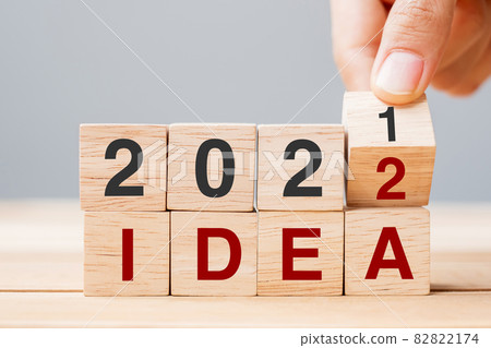 Businessman hand holding wooden cube and flip over block 2021 to 2022 IDEA on table background. Resolution, plan, Trend, change, start and New Year holiday concepts 82822174
