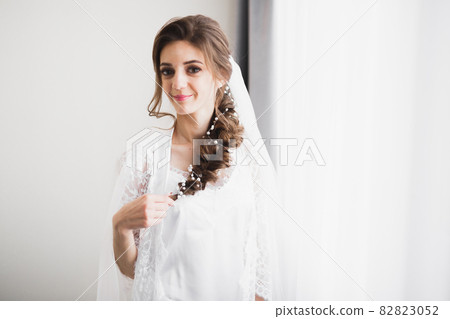 Beautiful bride wearing fashion wedding dress with feathers with luxury delight make-up and hairstyle, studio indoor photo shoot 82823052