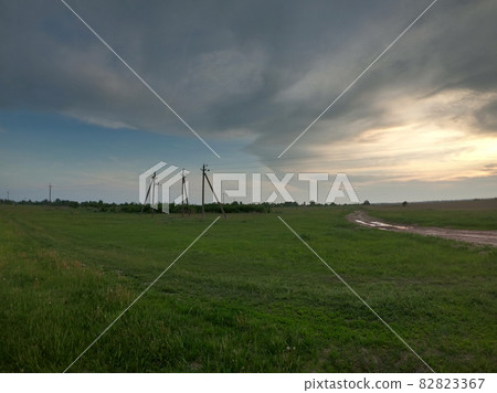 Pillars of power lines stand in the field in the evening. Evening landscape. Pillars of power lines stand in the field in the evening. Evening landscape. 82823367