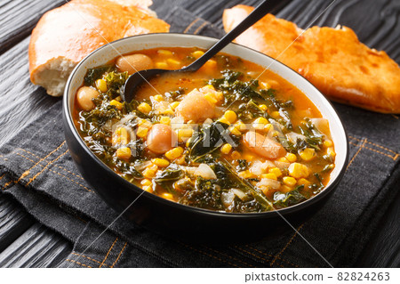 Vegetarian Turkish Kara lahana corbasi spicy cabbage soup with kale, beans, tomatoes and corn closeup on the table. horizontal 82824263