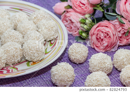 Plate with homemade coconut balls and pink flowers 82824793