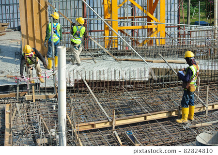 MALACCA, MALAYSIA -MAY 16, 2016: Construction workers fabricating steel reinforcement bar at the construction site in Malacca, Malaysia. The reinforcement bar was ties together using tiny wire. MALACCA, MALAYSIA -MAY 16, 2016: Construction workers fabricating steel reinforcement bar at the construction site in Malacca, Malaysia. The reinforcement bar was ties together using tiny wire. 82824810