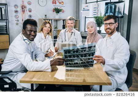 Diverse doctors sitting at desk with gadgets and x ray scan 82826416