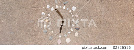 Sundial is lined with stones on sand of sea beach closeup background 82826536