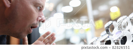 Surprised man looking at glass display case with expensive watch 82826551