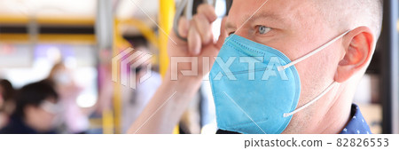 Man wearing protective medical mask riding bus and holding on to handrail Man wearing protective medical mask riding bus and holding on to handrail 82826553