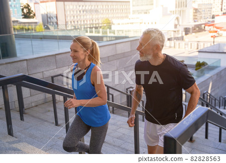 Active middle aged couple in sportswear running up a flight of stairs in city while working out together outdoors 82828563