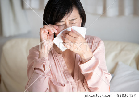 一個女人用紙巾和花粉症擤鼻涕的形象 一個女人用紙巾和花粉症擤鼻涕的形象 82830457