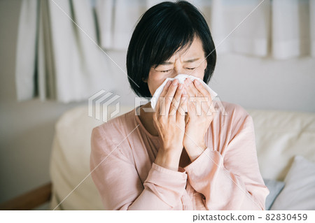 一個女人用紙巾和花粉症擤鼻涕的形象 82830459