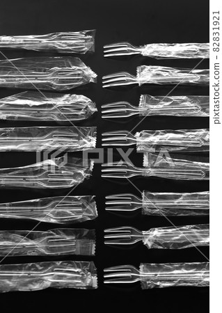Plastic spoons and forks on a black background Plastic spoons and forks on a black background 82831921
