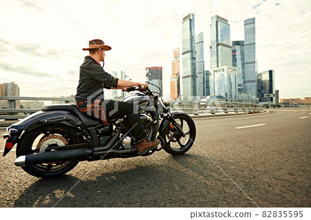 young man riding big bike ,motorcycle on city road against urban and town building scene. Motion blur young man riding big bike ,motorcycle on city road against urban and town building scene. Motion blur 82835595