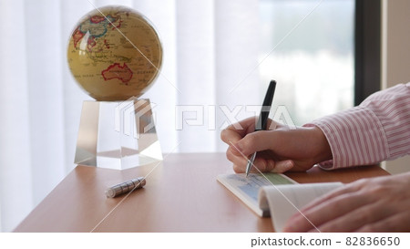 Close up of businesswoman writing a check with globe spinning inside the office 82836650