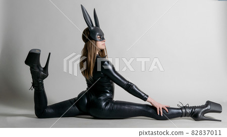 Sexy beautiful woman pole dancer posing in latex costume on background. Easter bunny concept. Sexy beautiful woman pole dancer posing in latex costume on background. Easter bunny concept. 82837011