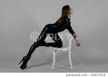 Sexy beautiful woman pole dancer posing in latex costume on background. 82837018