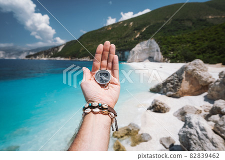 Hand holding a compass on the beach in background Hand holding a compass on the beach in background 82839462
