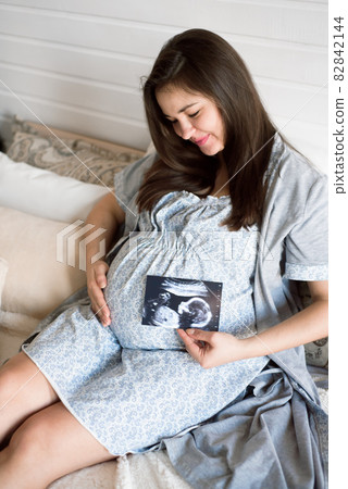 Pregnant woman looking at baby ultrasound scan. Pregnant woman looking at baby ultrasound scan. 82842144