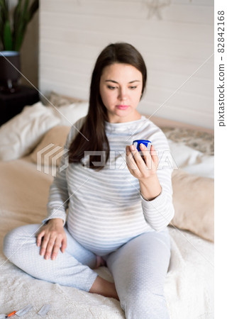 A pregnant woman checks her blood sugar using a blood glucose meter. 82842168