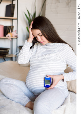 Pregnant woman holding glucose meter with result of measurement sugar level, concept of diabetes 82842169