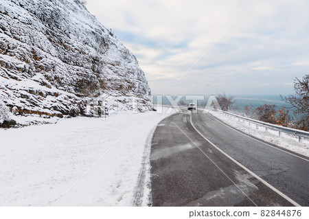 Winter time with snow trees, road with automobile and ocean at background. Winter landscape 82844876