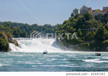 Boat with people floating to the waterfall the Rhine Falls 82845361