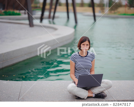 female student working with laptop in campus park. female student working with laptop in campus park. 82847817