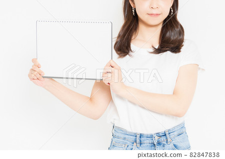 Young woman in a T-shirt with a small sketchbook 82847838
