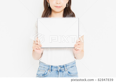 Young woman in a T-shirt with a small sketchbook 82847839