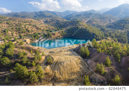 Lake in abandoned mine pit and waste heaps over mountains landscape in Xyliatos, Cyprus 82848475