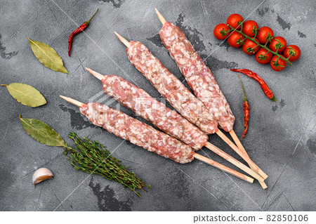 Raw beef and lamb meat kebabs sausages, with grill ingredients, on gray stone table background, top view flat lay 82850106