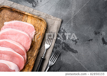 Raw organic meat. Pork steaks, fillets for grilling, baking or frying, on gray stone table background, top view flat lay, with copy space for text Raw organic meat. Pork steaks, fillets for grilling, baking or frying, on gray stone table background, top view flat lay, with copy space for text 82850133