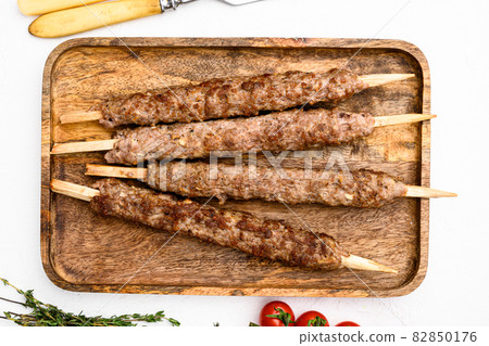 Shish kebab on a stick, from ground land mutton meat, on white stone table background, top view flat lay Shish kebab on a stick, from ground land mutton meat, on white stone table background, top view flat lay 82850176