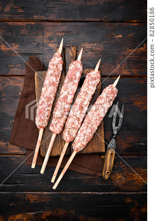Fresh Raw kofta or lula kebabs skewers, on old dark wooden table background, top view flat lay Fresh Raw kofta or lula kebabs skewers, on old dark wooden table background, top view flat lay 82850186