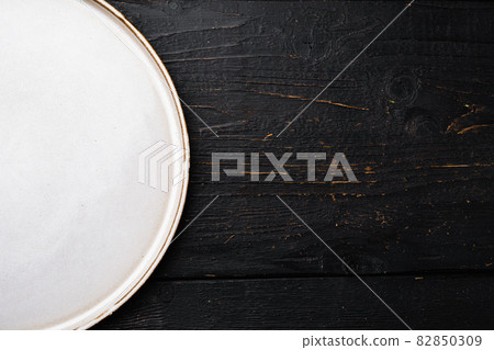 White rustic ceramic plate with copy space for text or food with copy space for text or food, top view flat lay , on black wooden table background White rustic ceramic plate with copy space for text or food with copy space for text or food, top view flat lay , on black wooden table background 82850309