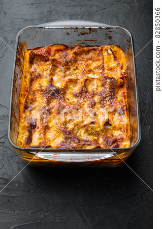 Baked meat lasagna, in baking tray, on black stone background Baked meat lasagna, in baking tray, on black stone background 82850366