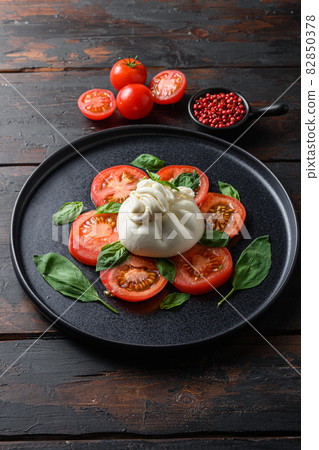 Burrata, Italian fresh cheese made from cream and milk of buffalo or cow. on black plate old wood table planks Burrata, Italian fresh cheese made from cream and milk of buffalo or cow. on black plate old wood table planks 82850378