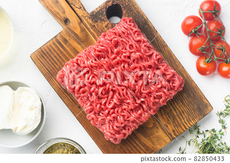 Homemade minced meat in a black bowl with ingredients. Fresh Raw mince for cooking meatballs, on white stone background, top view flat lay 82850433