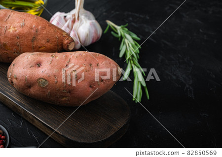 Sweet potato or batat with herbs and spices on black background with space for text 82850569